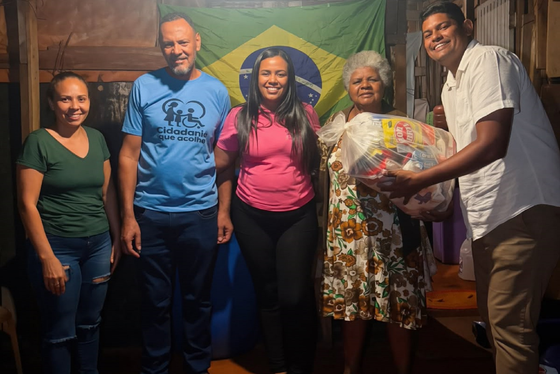 Voluntários da Cidadania que Acolhe entregam uma cesta básica a uma senhora